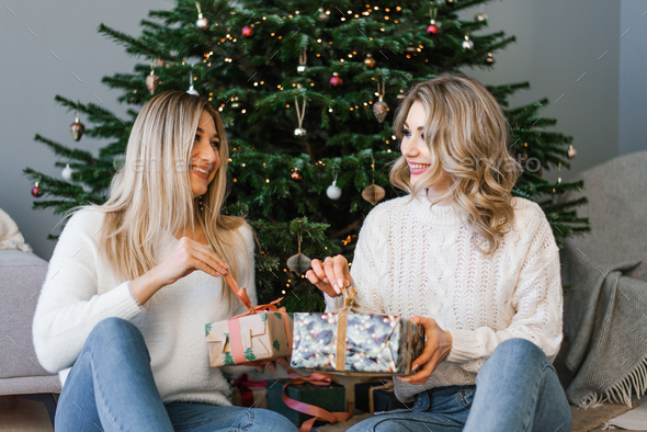 Two happy young girls laugh, friends give each other gifts during the ...