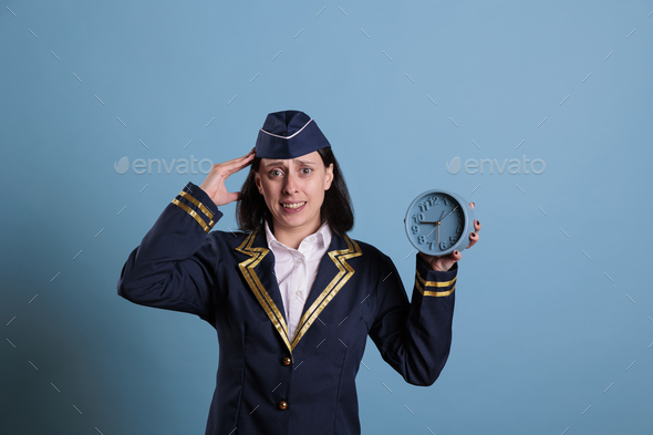 Anxious flight attendant holding retro alarm clock, running late