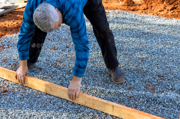 Building the deck foundation for the backyard shed by leveling two by four wood lumber on gravel for