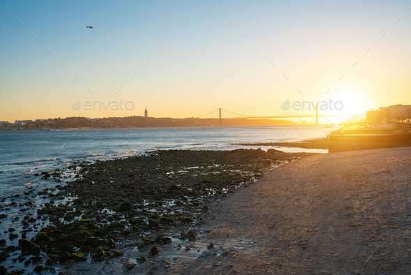 Tagus River at sunset with 25 de Abril Bridge and Sanctuary of Christ the King - Lisbon, Portugal - Stock Photo - Images