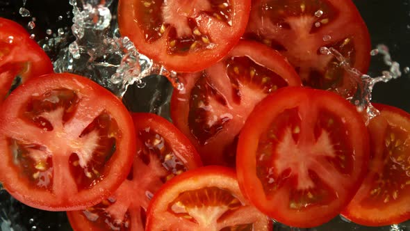 Super Slow Motion Shot of Tomato Slices Falling Into Water on Black Background at 1000Fps. alt
