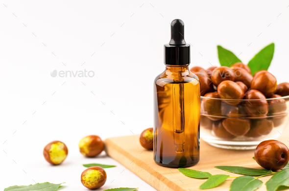 Jojoba oil in a bottle with a dropper and fresh jojoba fruit