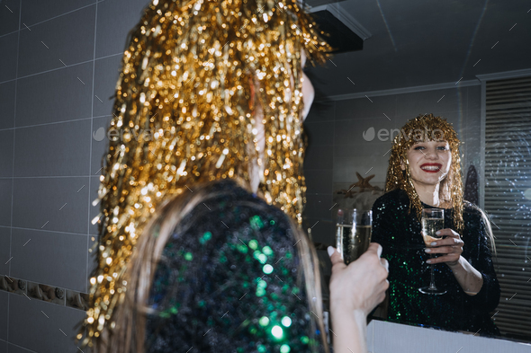 Beautiful woman with holiday makeup and gold shiny foil wig holding glass of champagne. - Stock Photo - Images