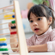 A young cute Asian girl is using the abacus with colored beads to learn how to count at home - PhotoDune Item for Sale