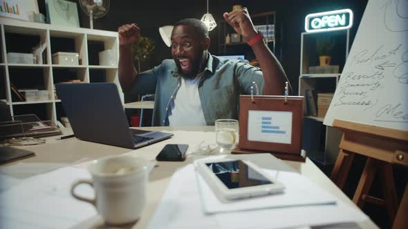 Satisfied African American Man Celebrating Success in Hipster Coworking. alt