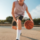 Concentrated boy dribbling basketball on sports ground - PhotoDune Item for Sale