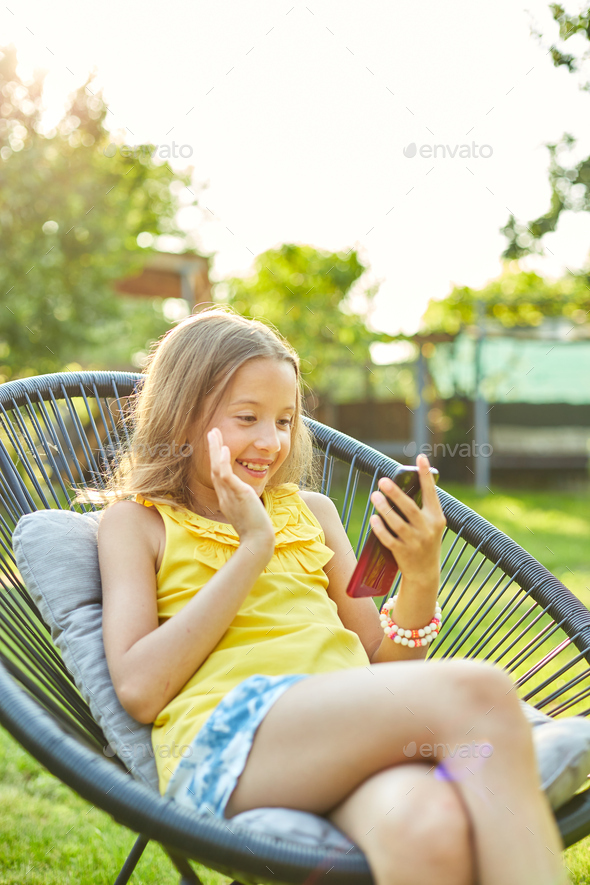 Happy kid girl holding smartphone having video call with friend distantly - Stock Photo - Images