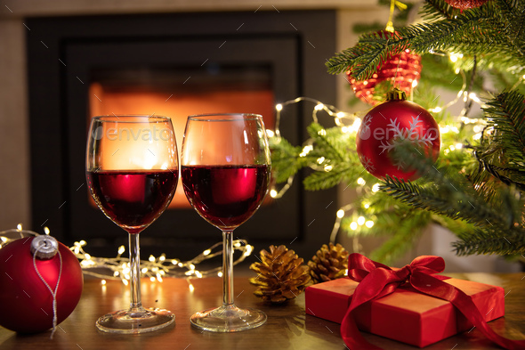 Christmas celebration. Red wine glasses, Xmas presents and decoration on table - Stock Photo - Images