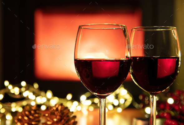 Christmas celebration. Red wine glasses and decoration on table, fireplace background.  - Stock Photo - Images