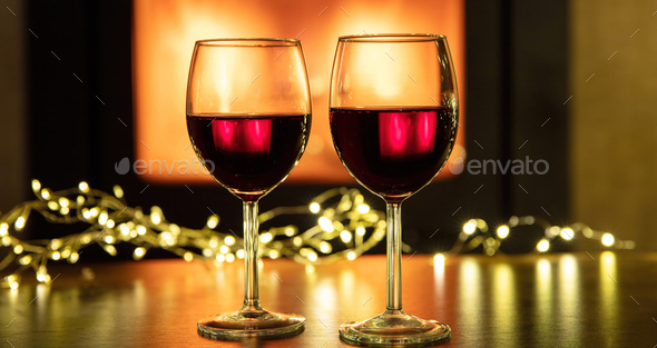 Christmas celebration. Red wine glasses and decoration on table, fireplace background. - Stock Photo - Images