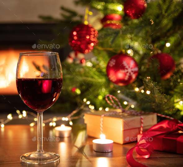 Christmas celebration. Red wine glasses, Xmas presents and decoration on table, fireplace background - Stock Photo - Images
