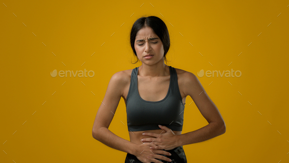 Sick ill Indian woman suffering from stomach ache holding belly feeling abdominal menstrual pain
