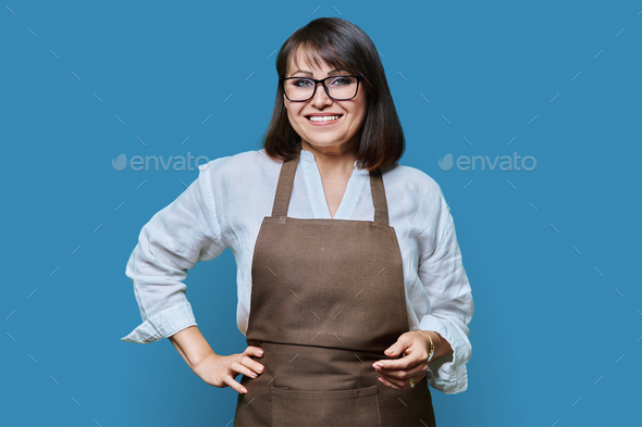 Confident middle aged woman in apron looking at camera on white background - Stock Photo - Images