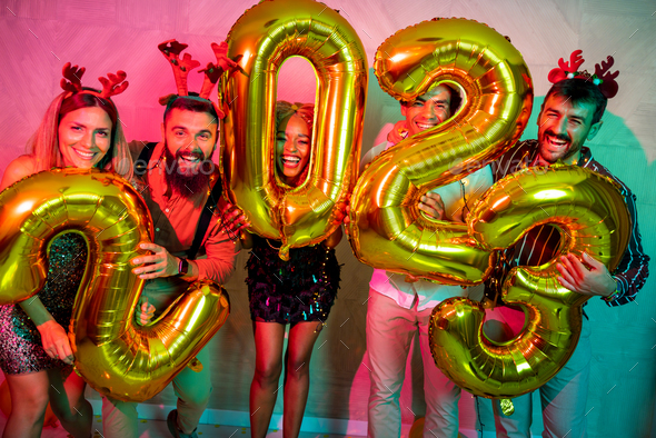 Friends holding giant balloons shaped as numbers 2023 representing the upcoming New Year - Stock Photo - Images
