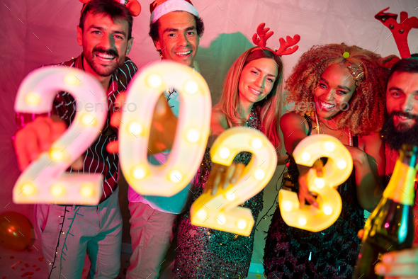 Friends holding illuminative numbers 2023 at New Year party - Stock Photo - Images