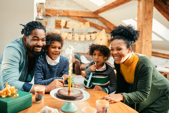 Cheerful African American family celebrating girl's Birthday and having fun at home. - Stock Photo - Images