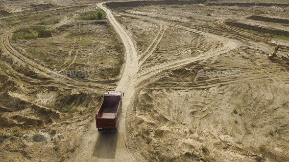 Dump truck driving on quarry area. Scene. Top view of dump truck driving through desert area with