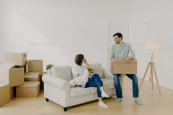 Positive woman and man pose in empty spacious room during relocation day - Stock Photo - Images