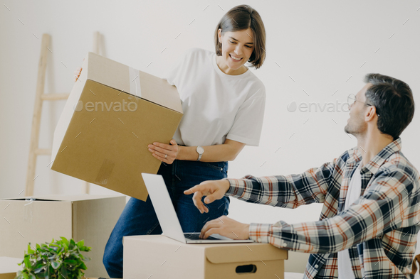 Happy young man points into laptop computer, searches new design for flat - Stock Photo - Images