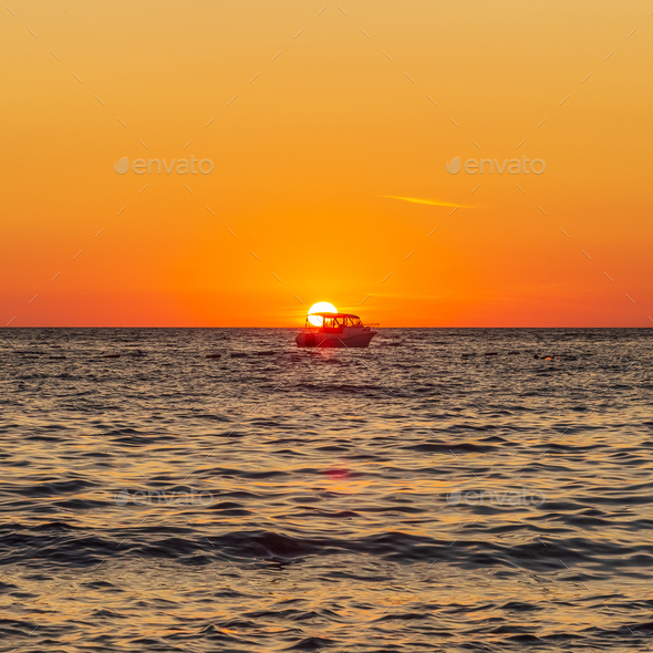 Fishing boat in the middle of the sea at sunset
