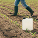 Herbicide jug container in corn seedling field, farmer walking in background - PhotoDune Item for Sale