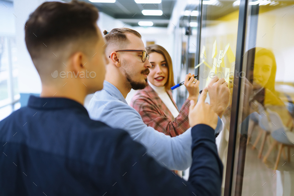 Young business people discussing and planning strategy Front of glass wall marker and stickers.