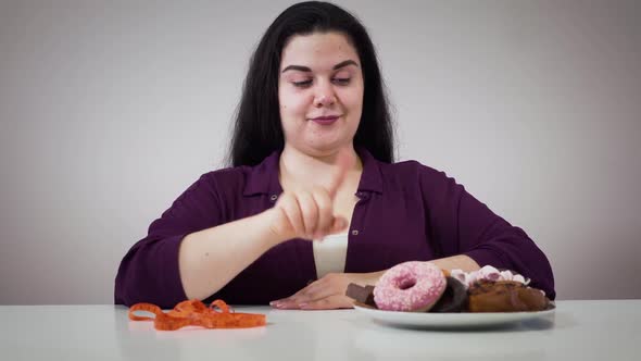 Portrait of Smiling Caucasian Obese Girl Sitting in Front of Sweets and Measure Tape. Fat Woman alt