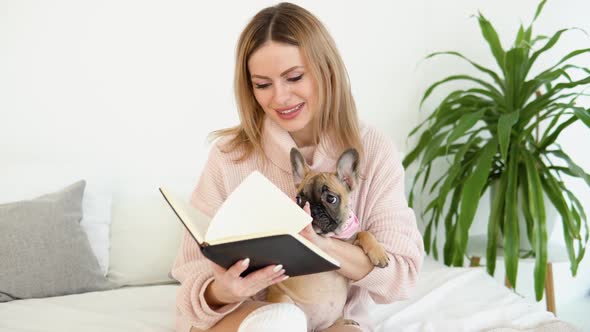 A Young Woman in a Cozy Powder Pink Sweater and White Stockings Sits on the Bed with Her Dog and alt