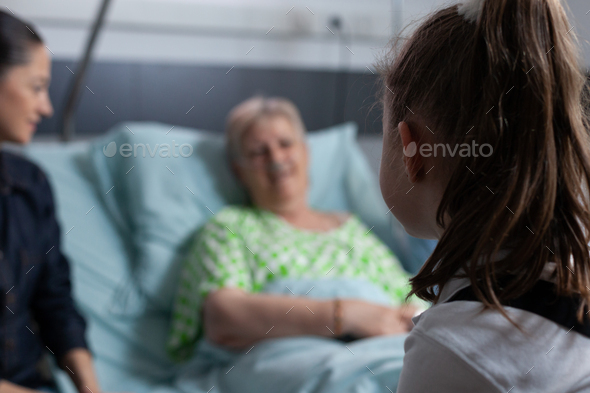 Family visiting recovering geriatric patient in medical clinic room - Stock Photo - Images