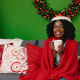Smiling young african woman sitting on sofa in living room on Christmas Eve - PhotoDune Item for Sale