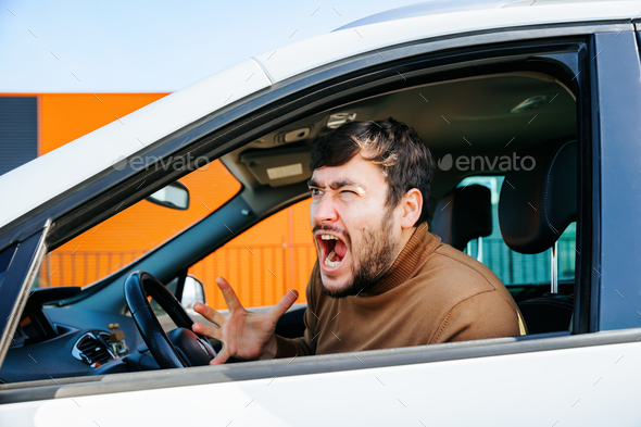 american disturbed and furious bearded chauffeur man gesticulates and yelling in the interior