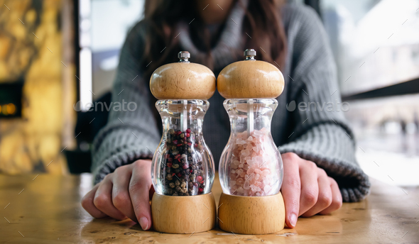 Close up of bottles of pink salt and pepper in containers with grinder  prepared. Stock Photo by puhimec