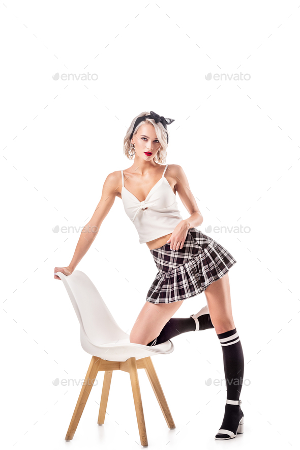 sexy woman in schoolgirl clothing and knee socks on chair isolated on white