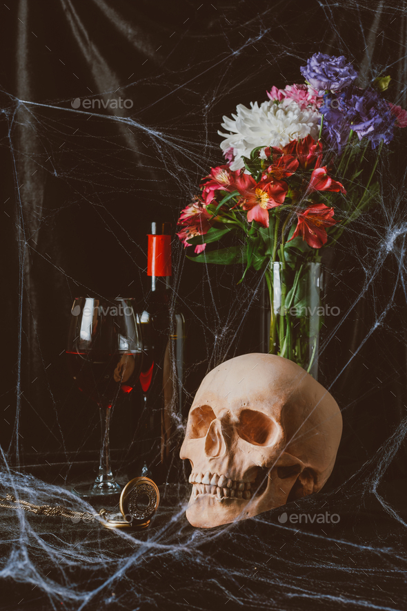 skull, red wine, vintage clock and flowers on black cloth with spider web