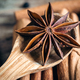 Star anise on a wooden spoon on a blurred background of cinnamon sticks. - PhotoDune Item for Sale