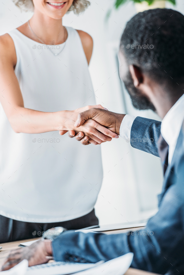 cropped image of multicultural businesspeople shaking hands in office - Stock Photo - Images