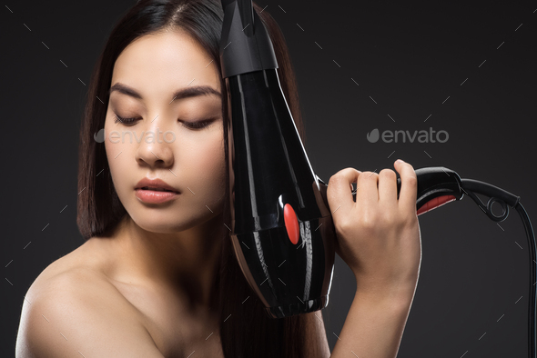 portrait of asian woman with hair dryer isolated on black - Stock Photo - Images