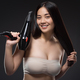portrait of smiling asian woman with hair dryer looking at camera isolated on black - PhotoDune Item for Sale