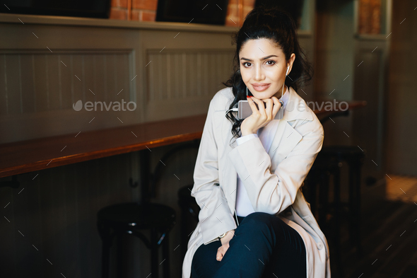 Horizontal portrait of fashionable woman with dark eyes and hair having pure skin looking in camera - Stock Photo - Images