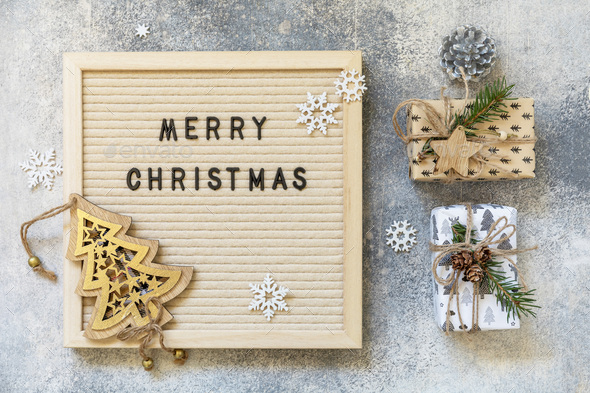 Cozy Christmas mood. Merry Christmas lettering on letter board, gifts boxs and holidays decorations.