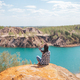 Young woman sitting on the top of mounting and feeling free and looking at the blue lake - PhotoDune Item for Sale
