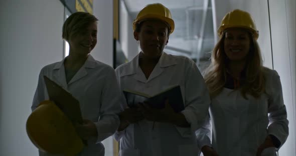 Female Engineers Walking through Corridor, Chatting and Laughing alt