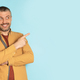 Happy middle aged caucasian man pointing aside at copy space over blue studio background, panorama - PhotoDune Item for Sale