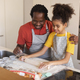 Black father and daughter rolling up dough while baking together in kitchen - PhotoDune Item for Sale
