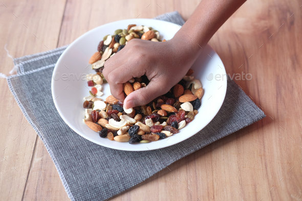  hand pick many mixed nuts on plate