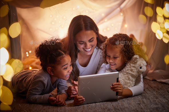 Mother and children live streaming movies on tablet or digital kids app in a tent camping at night