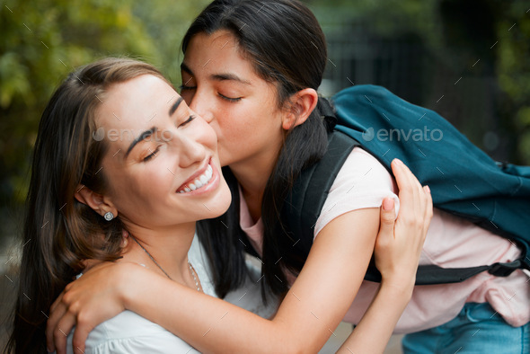 Happy, smiling and young daughter kissing her mother, hugging and greeting before school in the mor