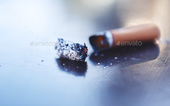 Smoke, ash and burning cigarette butt on table, tobacco addiction awareness and prevention of risk
