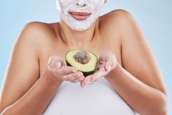 Beautiful young mixed race woman wearing a face mask peel and posing with an avocado isolated in st
