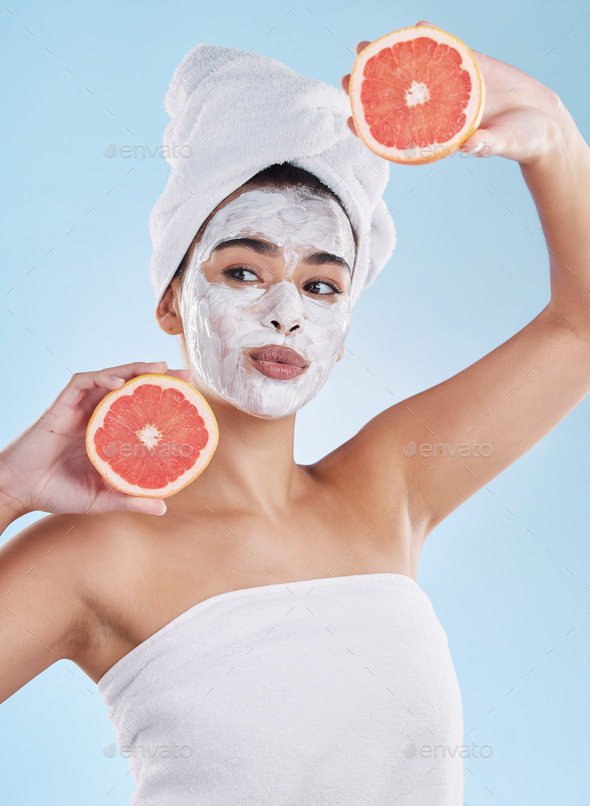 Beautiful young mixed race woman wearing a face mask peel and towel while posing with a grapefruit.